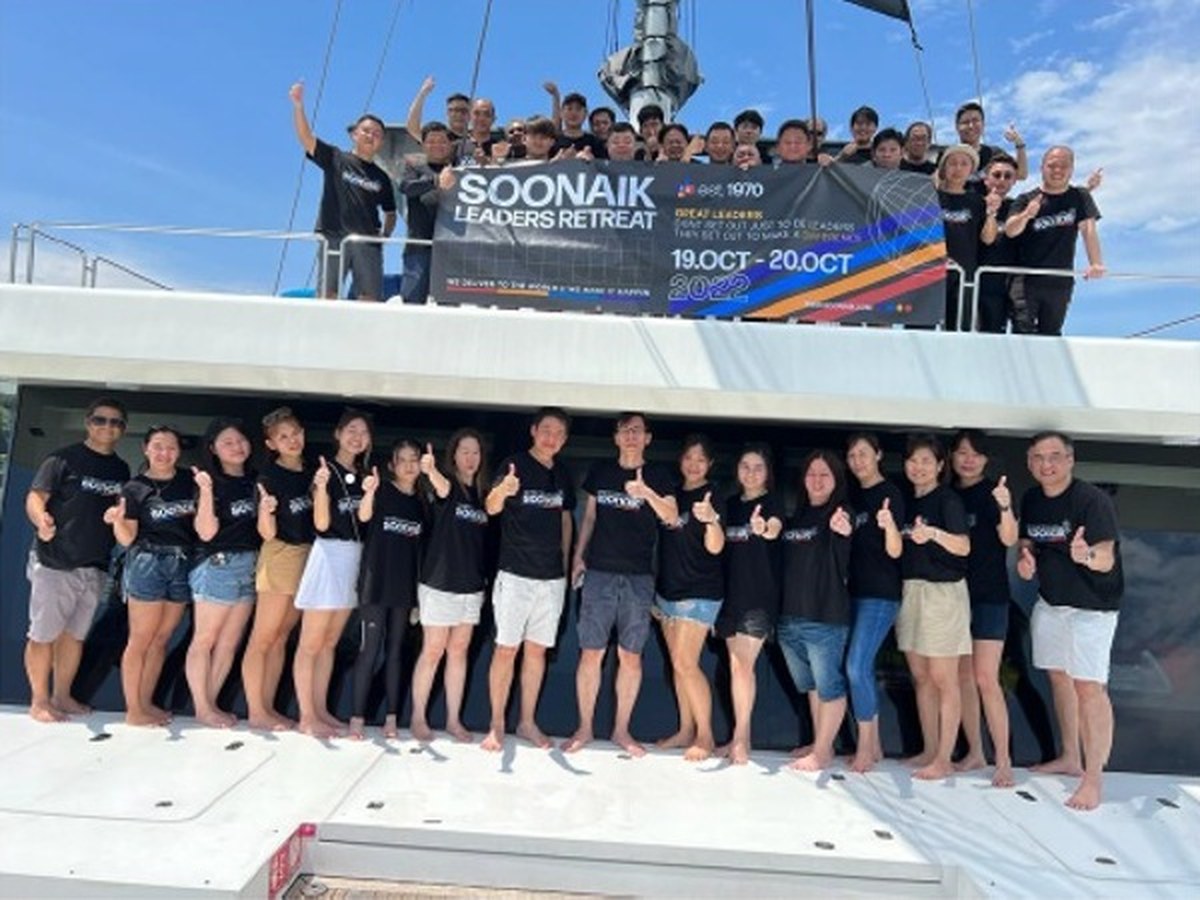 Soon Aik team members at the Leaders Retreat, thumbs up on a boat deck